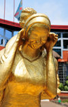 Goma, Nord-Kivu, Democratic Republic of the Congo: gilded statue of an African woman with a baby on her back - grin - Hotel Vip Palace in the background, Blvd Kanyamuhanga - photo by M.Torres