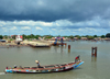 Barra, The Gambia: wooden fishing boat on the River Gambia estuary, passing in front of Barra's main pier - dark sky - photo by M.Torres