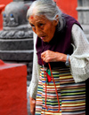 Kathmandu, Nepal: an old Tibetan woman recites prayers around a Buddhist temple - photo by E.Petitalot