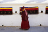 Kathmandu valley, Nepal: Bodhnath temple complex - Buddhist ritual - turning the wheel of Dharma - monk with mani wheel walks along a wall with prayer wheels - photo by W.Allgwer