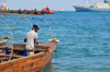 Stone Town, Zanzibar, Tanzania: a fisherman prepares his wares - boat seen from Mizingani Road - photo by M.Torres